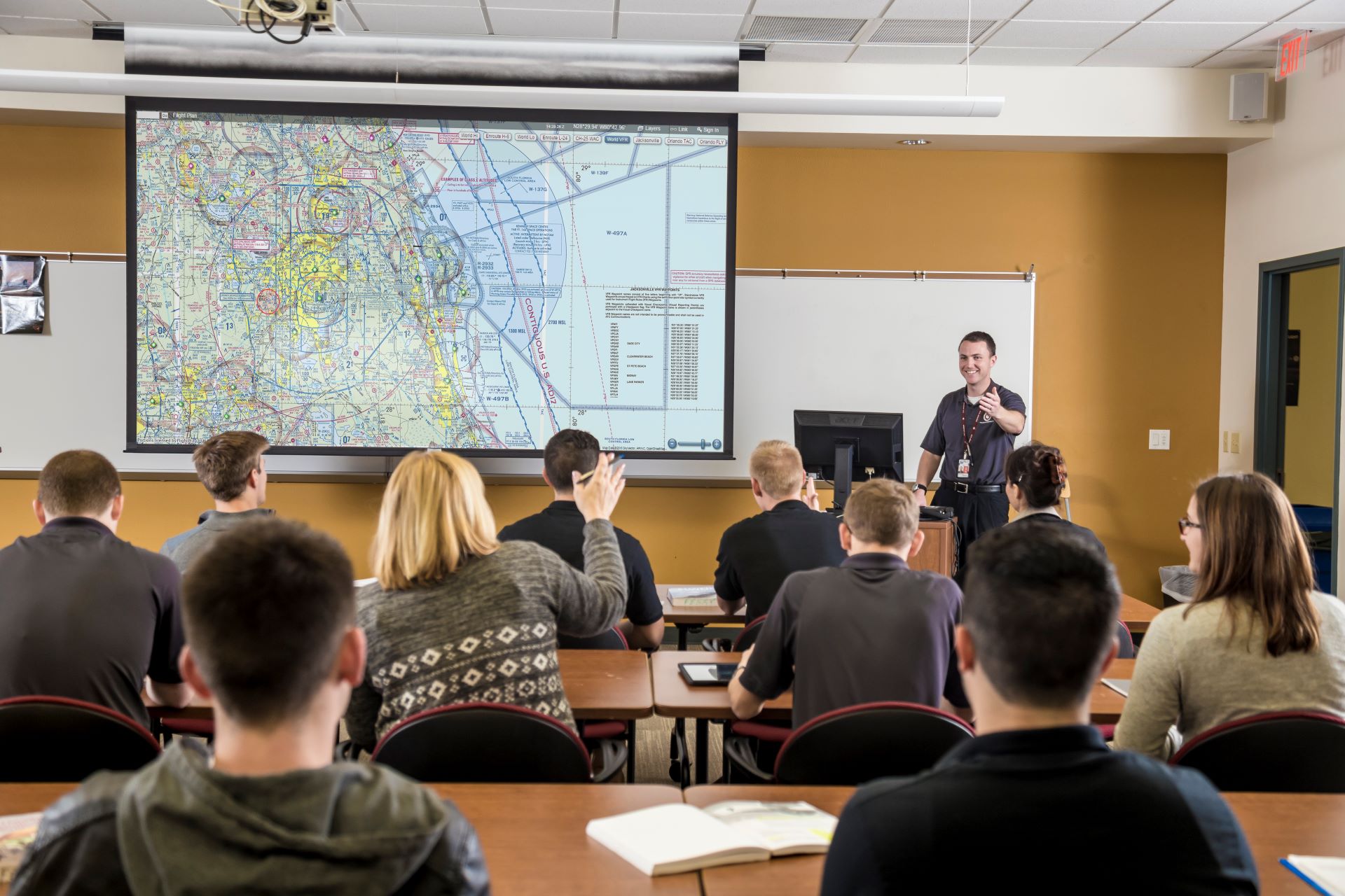 A classroom full of students with a presenter in front of a map